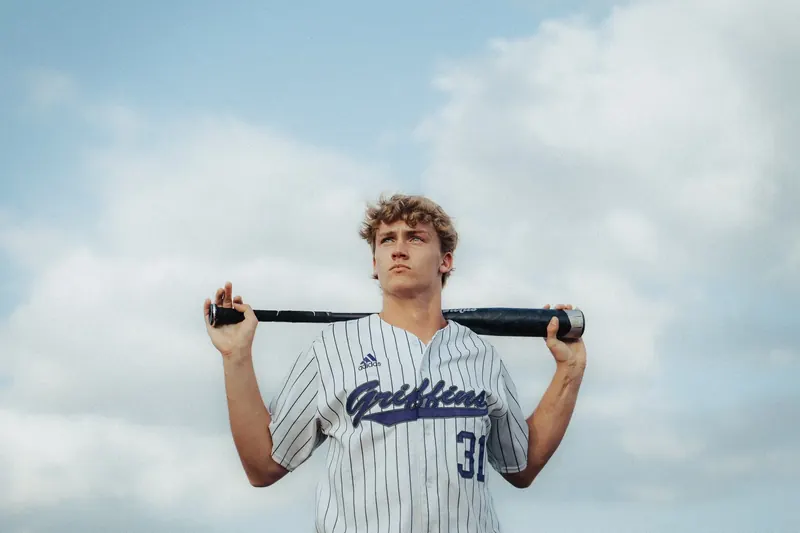 Baseball player in a dark uniform photographed from behind on the field at dusk