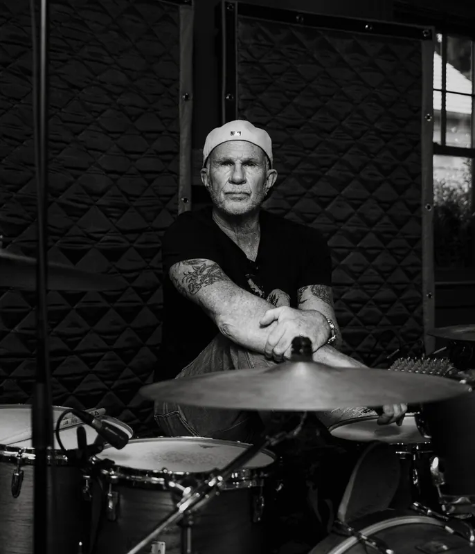 Black and white portrait of drummer Chad Smith seated at a recording console