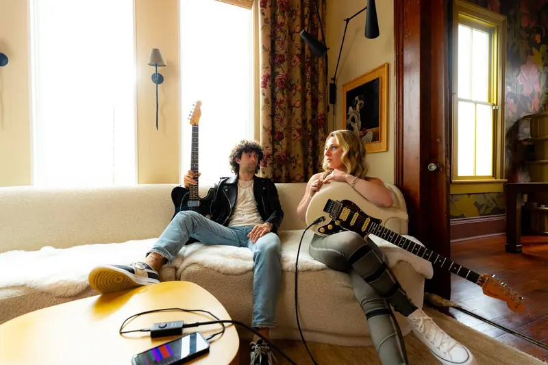 Dre Dimura and Alyssa Day playing guitar together in a bright styled interior for the Fender Studio app launch