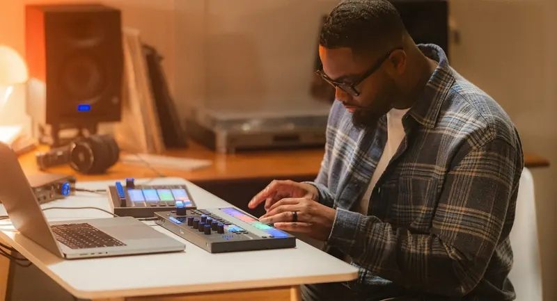 Producer using a Fender Motion controller alongside a laptop in a home studio