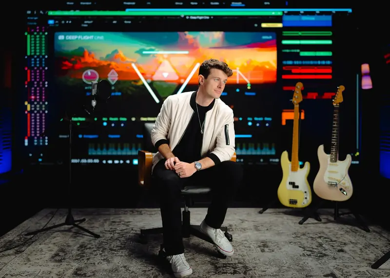 Producer Josh Cumbee at a keyboard workstation in a dark studio lit with coloured accents