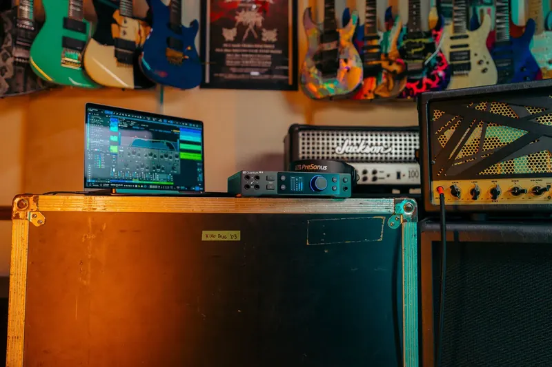 Brandon Ellis playing electric guitar in a dark studio lit with red accent light